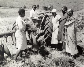 A communal ploughing team. A team of African farm workers pause to chat around a tractor pulling a