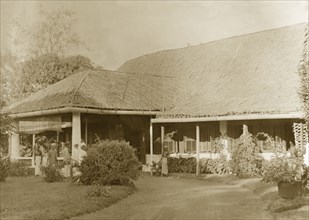 Colonial bungalow, Burma (Myanmar). Several servants stand on the driveway at the entrance to a