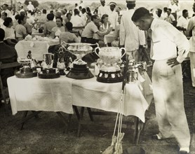 Golf trophies, Burma (Myanmar). An interested member of the press surveys a selection of golf