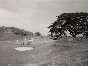 Playing golf, Rangoon. Golfers play a round on an uneven section of the golf course at Rangoon Golf