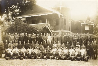 Group portrait outside a colonial house. A large number of formally dressed European men and women