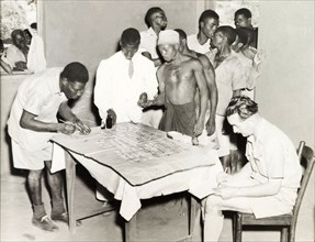 Blood samples at village dispensary. A group of African men queue at a dispensary, where two