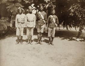 African Policemen. Outdoors portrait of four uniformed African policemen. They stand barefoot in a