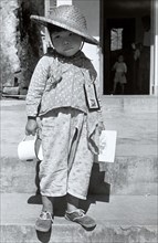 Refugee from China. A refugee boy from China stands on steps infront of an open doorway with an