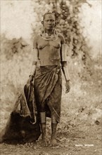Maasai woman. Full-length portrait of a semi-naked Maasai woman wearing metal necklaces, ear, arm