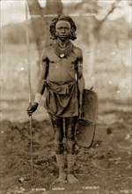 Kikuyu warrior. Full-length portrait of a Kikuyu man wearing neck ornaments and a waist cloth and