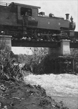 Train on washed-out bridge. A Uganda Railways locomotive pauses while crossing a damaged bridge on
