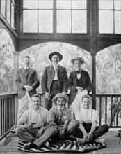 Men on a zebra skin rug. Informal group portrait of six European men on the wooden veranda of a