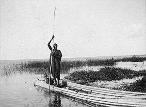 Reed canoe on Lake Victoria. A man stands at the rear of a canoe made from long reeds lashed
