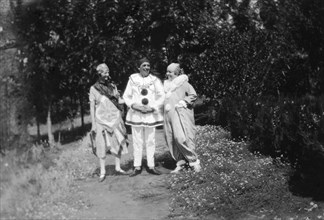 Christmas fancy dress. Three Europeans pose on a garden path wearing fancy dress. Charles Bungey