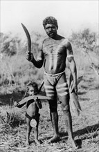Aborigines with boomerangs. An aboriginal man holding several wooden boomerangs poses for the