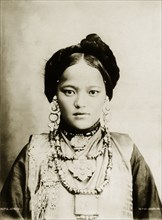 Bhutia woman. Portrait of a finely dressed young Bhutia woman in traditional costume. Her hair is