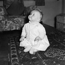 Baby at the Russel's house. A baby sitting on a patterned rug at the Russel's family house looks