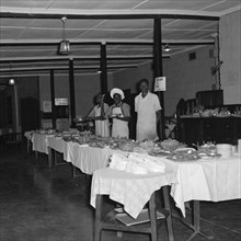 Buffet for the SJAK dance. Three African men wait to serve behind a long line of buffet tables