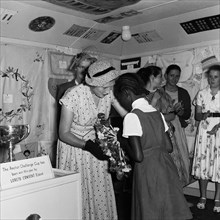Coats and Clark prizegiving. A young African schoolgirl receives a flower arrangement as a prize