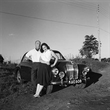 Sue and John Paton. Sue and John Paton relax, leaning back against their MG car in the evening