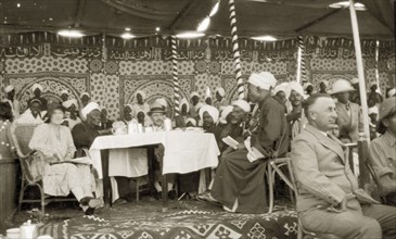 Kings' Day celebrations. A large, mostly male, crowd sit around tables beneath an elaborately