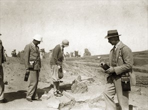 Archaeological excavation. Two European men with cameras or recording equipment accompany a woman