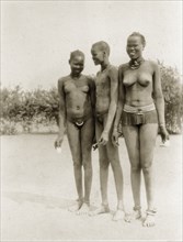Sudanese youths. Three Sudanese youths stand closely together, naked apart from the minimal