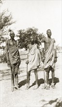 Three Nuer men. Three young Nuer men wear traditional dress and carry sticks. They are adorned with
