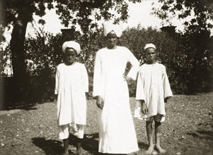Mess servants. Three African mess servants, an adult male and two boys, stand side by side in a