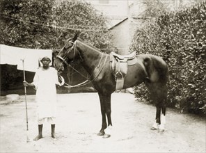 Tinto the horse. A young African servant stands polo mallet in hand, displaying a horse captioned