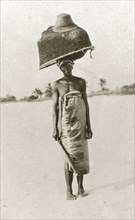 East African fisherwoman. An east African fisherwoman balances a large basket and fishing net on