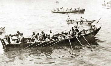 African oarsmen. A group of African oarsmen aboard a narrow barge take a break from rowing.
