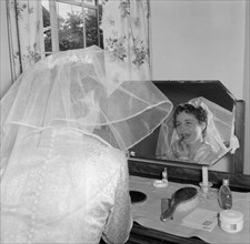 A bride at her dressing table. The Patterson bride applies her lipstick at a dressing table mirror