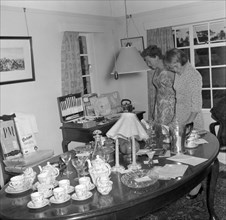 Inspecting the wedding presents. Two women examine wedding presents on display at the Patterson