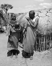 Lesanguniguni and his wife. A Samburu man identified as 'Lesanguriguri' chats to his young wife who