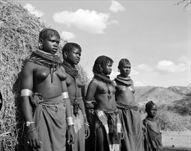 Turkana village girls. Portrait of four young Turkana women and a child outside a thatched village