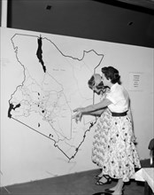 Map of Kenya at the KNFU stand. Two European women point at a large scale map of Kenya displayed at