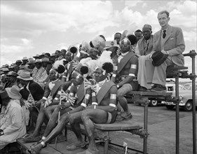 Turkana welcoming committee. Turkana men in ceremonial dress sit on a spectator stand amongst an