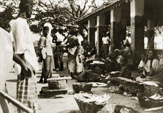 Ceylonian street market. Street traders sell goods from baskets on the floor at a busy open air