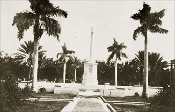 War memorial, Kingston. A war memorial stands in front of government buildings bordered by palm