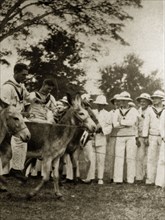 Donkey derby starting line. Uniformed sailors in the British Special Service Squadron entertain