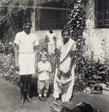 A colonial garden, India. An Indian servant and an ayah (nursemaid) entertain two young British