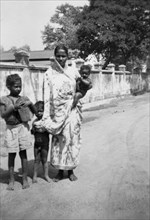 Indian woman with children. An Indian woman dressed in a sari stands, baby on hip, beside two