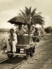Railway hand cart. Three men sit aboard a small railway cart fitted with a wooden seat, an unusual