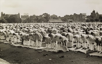 Prayers during Eid. Hundreds of Muslim men, standing bare-foot on prayer mats, bow their upper