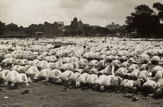 Kneeling in prayer for Eid. Hundreds of Muslim men, their shoes removed, kneel on prayer mats as