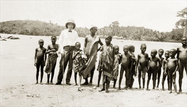 Children on the beach. A European stands on a beach surrounded by African children. Western Africa,