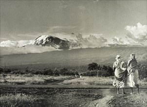 Kilimanjaro skyline. Two African women take in a view of Mount Kilimanjaro. Tanganyika Territory