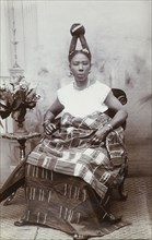 Woman with an elaborate hairstyle, Gold Coast. Studio portrait of a smartly dressed African woman