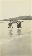 Out of water. Two European men wearing solatopi hats are carried above the water on the backs of