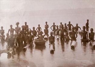 Children at lake shore, Gold Coast. A group of naked African people, mainly children, pose for the