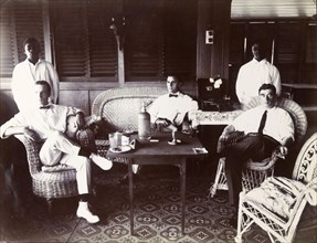 European staff relaxing in Swanzy's bungalow. Alfred Tamlin, A. M. Napolitano, and P. Kane relax in