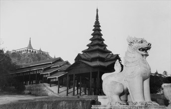 Sphinx statue at the Shwe Dagon Pagoda. A sphinx statue stands guard over a large wooden pagoda