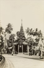 In the grounds of the Shwe Dagon Pagoda. View of a pagoda with a tiered roof and pillared entrance,